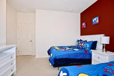 a bedroom with two beds and a red wall at Fantastic Townhouse in Lux community sleeps 8, 10' to Disney!! in Kissimmee