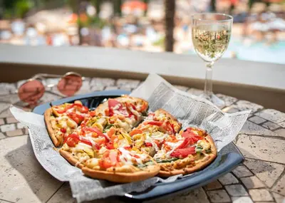 two pizzas on a plate on a table with a glass of wine at Floridays Orlando Two & Three Bed Rooms Condo Resort in Orlando