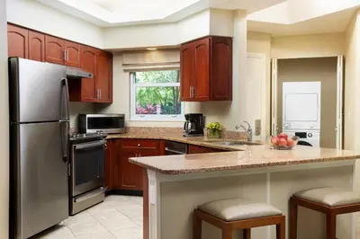 a kitchen with wooden cabinets and a stainless steel refrigerator at Sheraton Vistana Resort Villas, Lake Buena Vista Orlando in Orlando