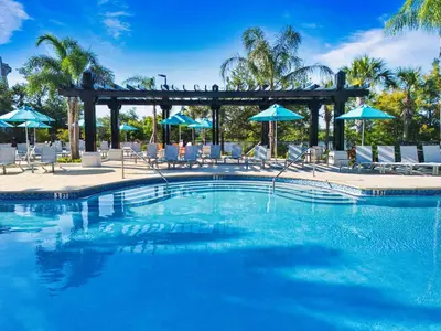 a large swimming pool with chairs and umbrellas at Vista Cay at Epic Universe - Luxury 4 bedroom condo in Orlando