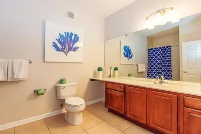 a bathroom with a toilet and a sink and a mirror at Vista Cay at Epic Universe - Standard 3 bedroom condo in Orlando