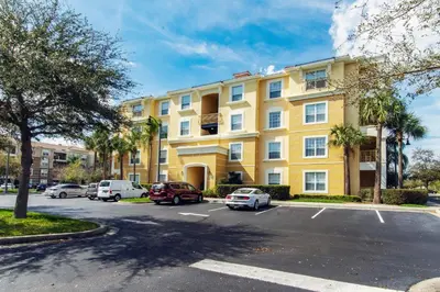 a yellow building with cars parked in a parking lot at Vista Cay at Epic Universe - Standard 3 bedroom condo in Orlando