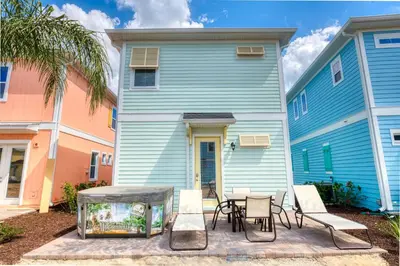 a blue building with chairs and a table in front of it at Sea Breeze Cottage Near Disney With Private Hot Tub & Margaritaville Resort & Island H20 Waterpark Access - 3016Sr in Orlando