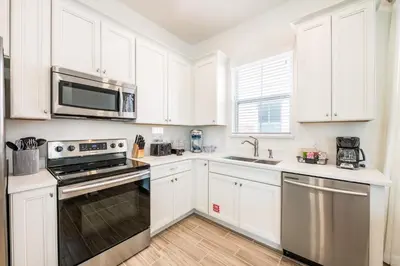 a kitchen with white cabinets and a stove top oven at Sea Breeze Cottage Near Disney With Private Hot Tub & Margaritaville Resort & Island H20 Waterpark Access - 3016Sr in Orlando