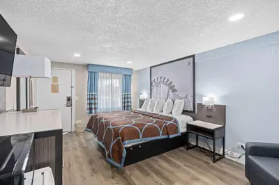 a hotel room with a bed with a painting on the wall at Super 8 by Wyndham Kissimmee-Orlando in Kissimmee
