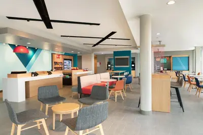 a lobby with chairs and tables and a cafeteria at avid hotels - Orlando International Airport by IHG in Orlando