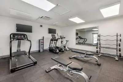 a gym with several tread machines and a mirror at Orbit One Vacation Villas in Orlando