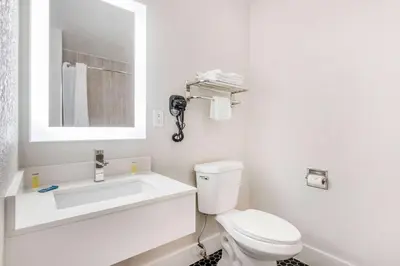 a white bathroom with a toilet and a sink at Super 8 by Wyndham Orlando Near Florida Mall in Orlando