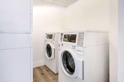a washer and dryer in a white laundry room at Super 8 by Wyndham Orlando Near Florida Mall in Orlando