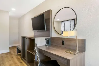 a room with a desk with a mirror and a tv at Super 8 by Wyndham Orlando Near Florida Mall in Orlando