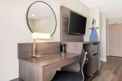 a room with a desk with a mirror and a tv at Super 8 by Wyndham Orlando Near Florida Mall in Orlando