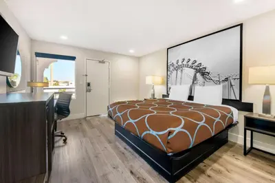 a hotel room with a bed and a desk at Super 8 by Wyndham Orlando Near Florida Mall in Orlando