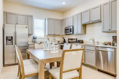 a kitchen with white cabinets and a wooden table and chairs at Sandy White Cottage Near Disney With Private Hot Tub & Margaritaville Resort & Island H20 Waterpark Access - 3001Sp in Orlando
