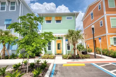 a row of colorful houses with trees in front at Key Lime Cabana Cottage Near Disney With Margaritaville Resort & Island H2O Access - 3062Kl in Orlando