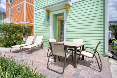 a patio with three chairs and a table on a house at Key Lime Cabana Cottage Near Disney With Margaritaville Resort & Island H2O Access - 3062Kl in Orlando