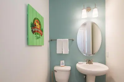 a bathroom with a sink and a toilet and a mirror at Sun Baked Cottage With Hot Tub Near Disney With Margaritaville Resort & Island H2O Access - 8089Dr in Orlando