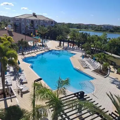 a large swimming pool with lounge chairs and a lake at 13-403 Your Vista Cay Home in Orlando