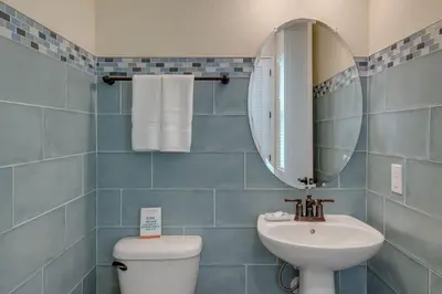 a blue tiled bathroom with a sink and a mirror at Breezy Cottage With Hot Tub Near Disney With Margaritaville Resort & Island H2O Access - 8069Dr in Orlando