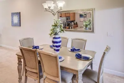 a dining room table with chairs and a vase with flowers at Storey Lake 4b3b town home with private pool in Kissimmee