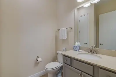 a bathroom with a toilet and a sink and a mirror at Cozy Cottage With Hot Tub Near Disney With Margaritaville Resort & Island H2O Access - 8056Dr in Orlando