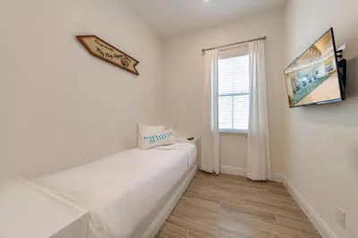 a white room with a bed and a window at Tropical Oasis Cottage With Private Hot Tub Near Disney With Margaritaville Resort & Island H2O Access - 3021La in Orlando