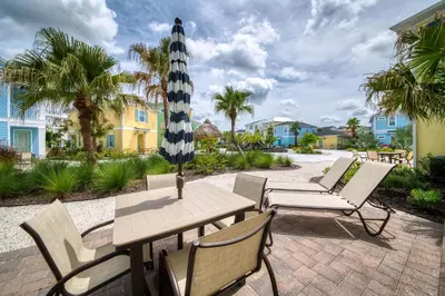 a patio with a table and chairs with an umbrella at Casa Del Mar Cottage Near Disney With Margaritaville Resort & Island H2O Access - 8009Ff in Orlando