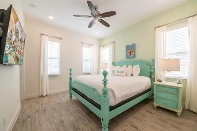 a bedroom with a green bed and a ceiling fan at Livin In Paradise Cottage With Private Hot Tub Near Disney With Margaritaville Resort & Island H2O Access - 8076Dr in Orlando