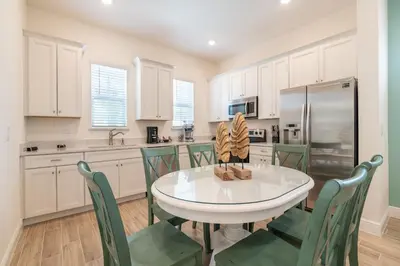 a kitchen with a white table and green chairs at We Be Jammin Cottage With Private Hot Tub Near Disney With Margaritaville Resort & Island H2O Access - 8020Dr in Orlando