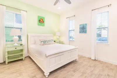 a white bedroom with a bed and two windows at It's All Fin & Games Cottage With Private Pool Near Disney & Margaritaville Resort & Island H20 Waterpark Access - 3090Ph in Orlando