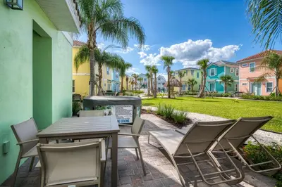 a patio with a table and chairs and palm trees at Seaweed Bay Cottage With Hot Tub Near Disney And Margaritaville Resort & Island H2O Access - 8061Dr in Orlando