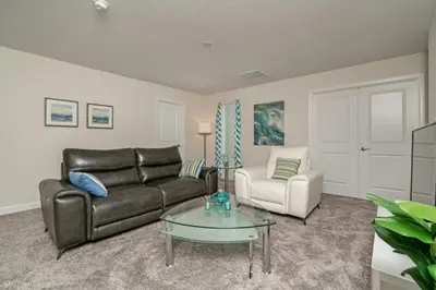 a living room with a leather couch and a glass table at 891Pbeach Amazing Champions Gate 8 Bedroom 5 Bed Villa in Orlando
