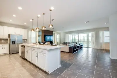 a large kitchen with white cabinets and a living room at Solara Resort 9 Bedroom 6 Bathroom Resort Villa Villa in Orlando