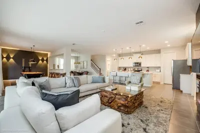 a large living room with white furniture and a kitchen at Solara Resort 9 Bedroom 6 Bathroom Resort Villa Villa in Orlando
