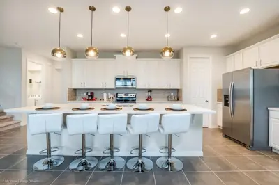 a kitchen with white cabinets and a large island with bar stools at Solara Resort 9 Bedroom 6 Bathroom Resort Villa Villa in Orlando