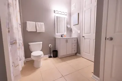 a bathroom with a toilet and a sink and a mirror at DISNEY PARKS- International Dr - Orlando Luxury Condominium- Fully Equipped - 3bed & 2 bath- in Orlando