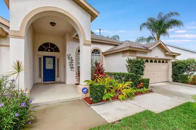 a house with a blue door and a driveway at #503 Stunning 4 Bed, 3 bath villa with southwest facing pool and spa in Orlando