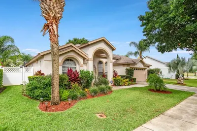 a house with a palm tree in a yard at #503 Stunning 4 Bed, 3 bath villa with southwest facing pool and spa in Orlando
