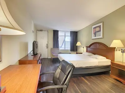 a hotel room with a bed and a desk and chairs at Stayable Orlando at Florida Mall in Orlando