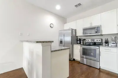 a kitchen with white cabinets and stainless steel appliances at Amazing Townhouse in gated community 10' to Disney! in Kissimmee
