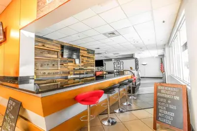 a bar in a restaurant with red stools at Ramada by Wyndham Flamingo Water Park in Kissimmee