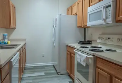 a kitchen with a white refrigerator and wooden cabinets at 2785AL-SVH Brand New Apartment! in Orlando