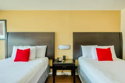 two beds in a hotel room with red pillows at Hotel Belair Orlando Near Florida Mall in Orlando