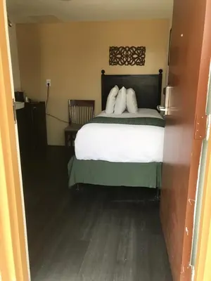 a bedroom with a bed with white sheets and pillows at Hotel Belair Orlando Near Florida Mall in Orlando
