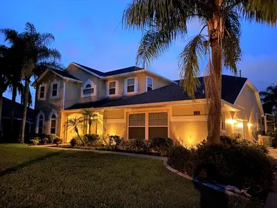 a house with a palm tree in front of it at Mickeys Pearl - Phenomenal 7BR with 4 Master Suites Privacy Pool & Hot Tub Gas BBQ - 2 miles to Disney in Orlando