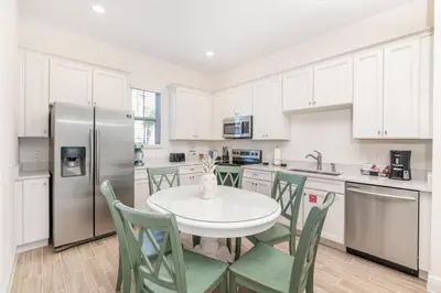 a kitchen with a table and chairs and a refrigerator at Salt Water Cottage Near Disney With Margaritaville Resort & Island H2O Access - 8012Dr in Orlando