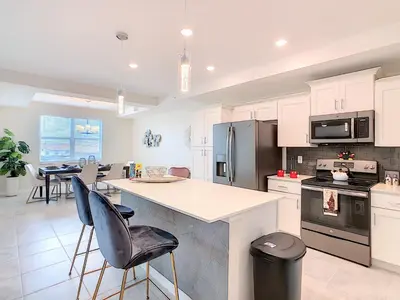a kitchen with white cabinets and a counter with chairs at Splendid Thematic 2BR with Waterpark in Kissimmee