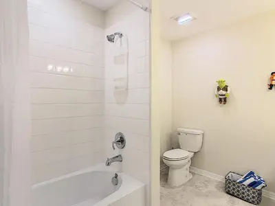 a white bathroom with a toilet and a shower at Lakeview Themed 2BR Condo with Waterpark Access in Kissimmee