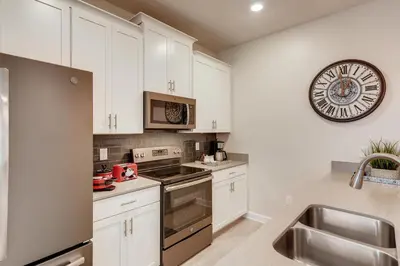 a kitchen with white cabinets and a clock on the wall at 4801 ML - Ideal Retreat Townhome Oasis with Pool in Kissimmee