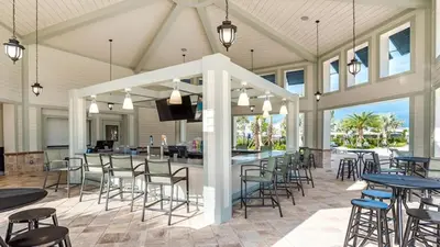 a covered patio with tables and chairs and a bar at 4801 ML - Ideal Retreat Townhome Oasis with Pool in Kissimmee
