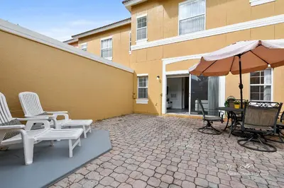 a patio with a table and chairs and an umbrella at 139PBD-SVH Lovely New Townhome! in Kissimmee